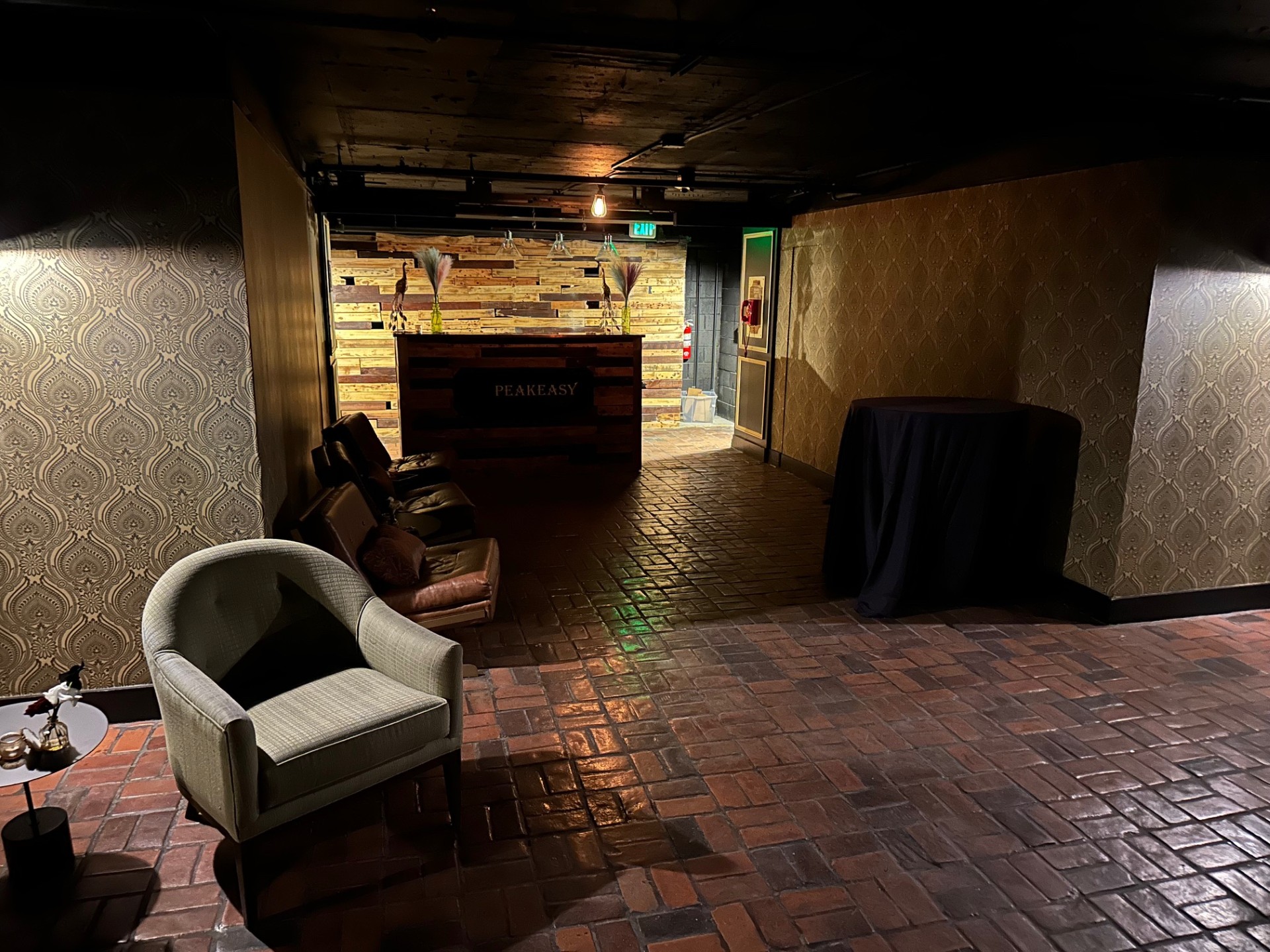 Inside the speakeasy showing brick floors, vintage decor, and the SPEAKEASY sign